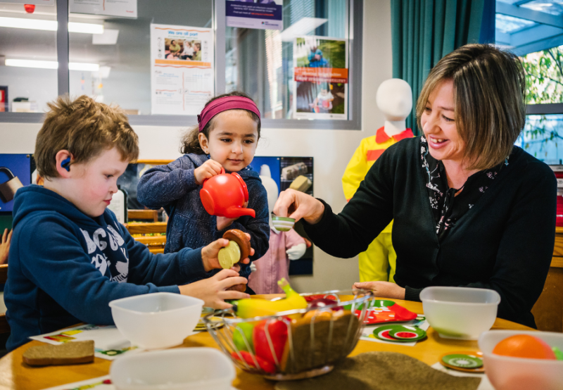 Educator and 2 children playing with a tea pot and tea cups