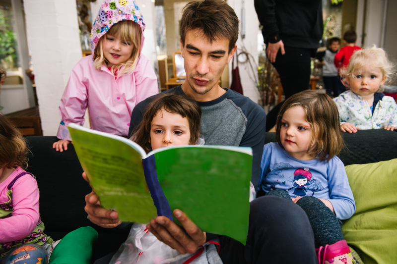 male educator reading to a group of young children