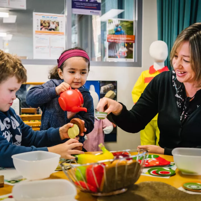 Educator and 2 children playing with a tea pot and tea cups