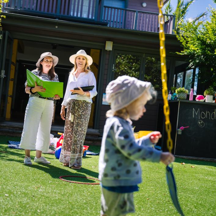 2 educators and a child in outdoor space