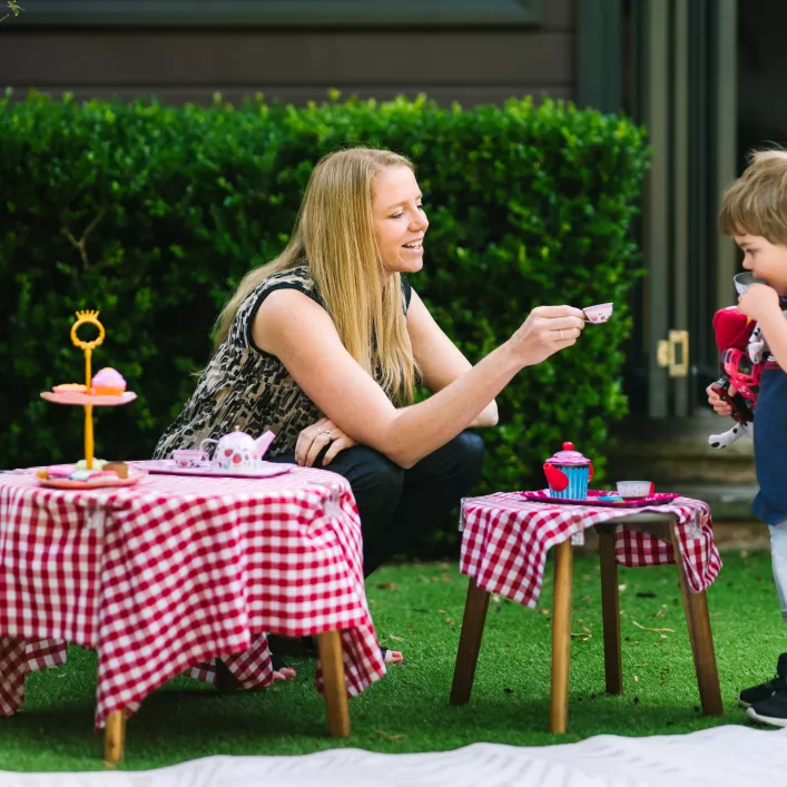 Educator with child in the garden having a tea party