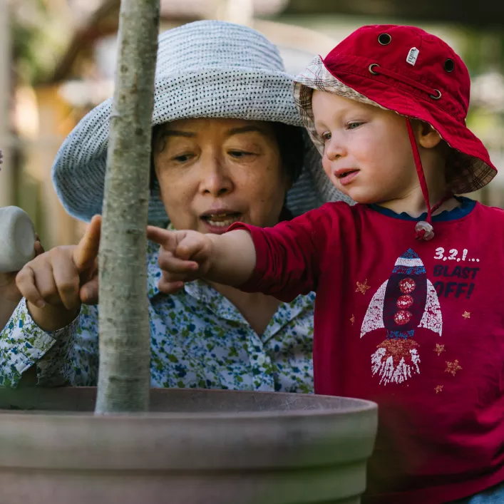 Educator with two children looking at a plant